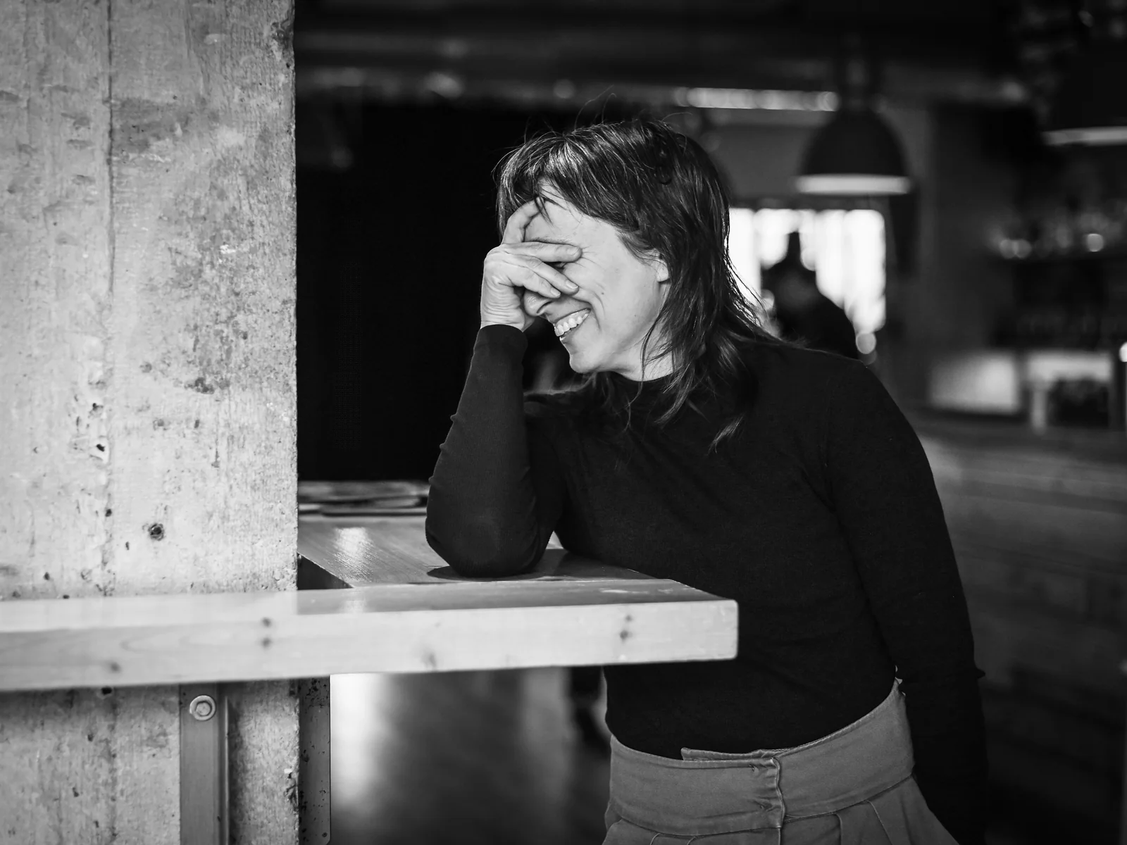 Černobílá fotografie smějící se Lucie Dlabolové v kavárně